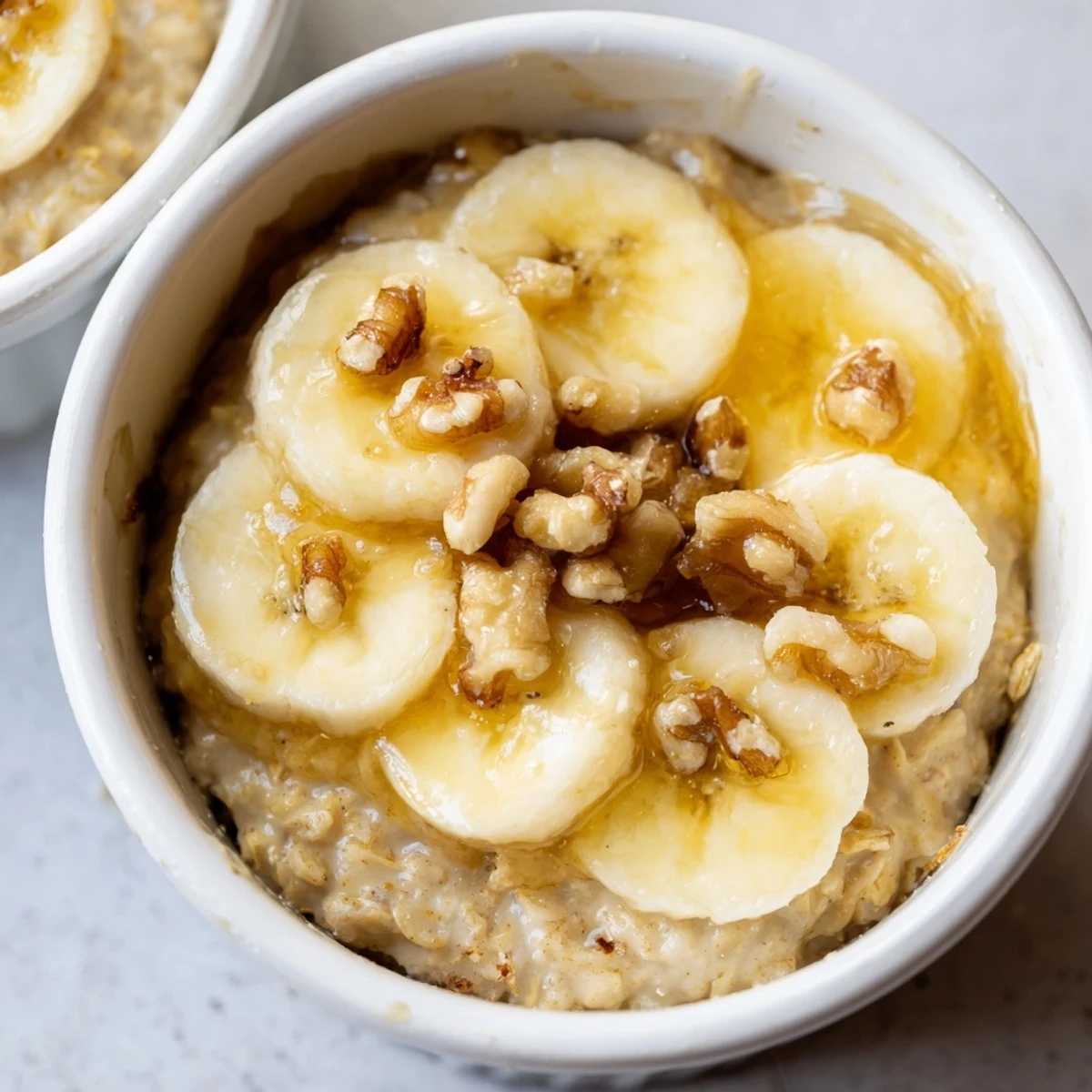 Individual ramekins brimming with baked oats, banana, and honey: a delicious American breakfast treat.