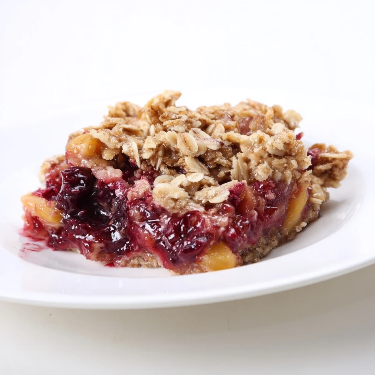 Steaming baked Fruit Crisp with golden oat topping, overflowing with bubbling, sweet fruit filling.