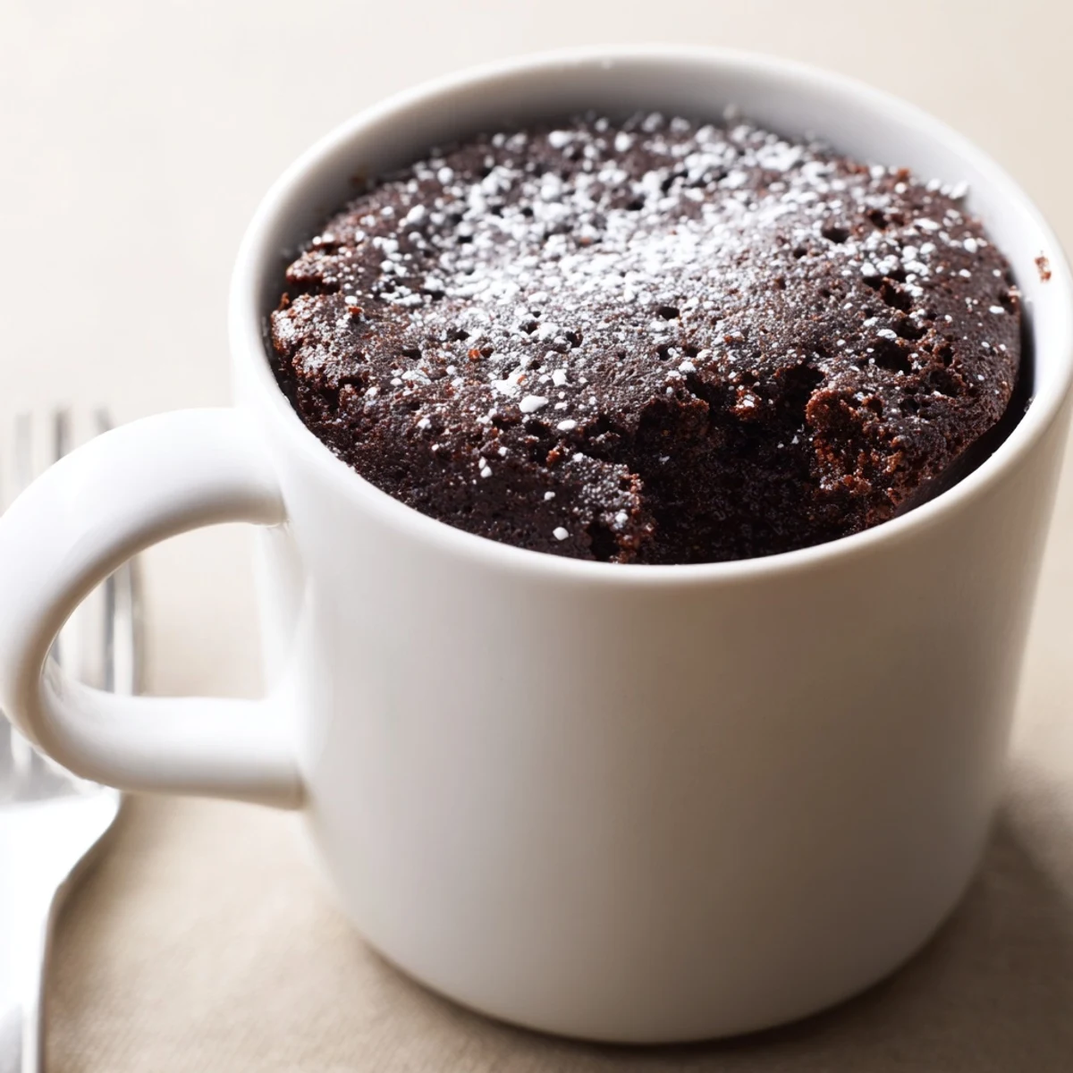 Steaming-hot, decadent Microwave Mug Cake filling a white mug, perfect for a fast dessert.