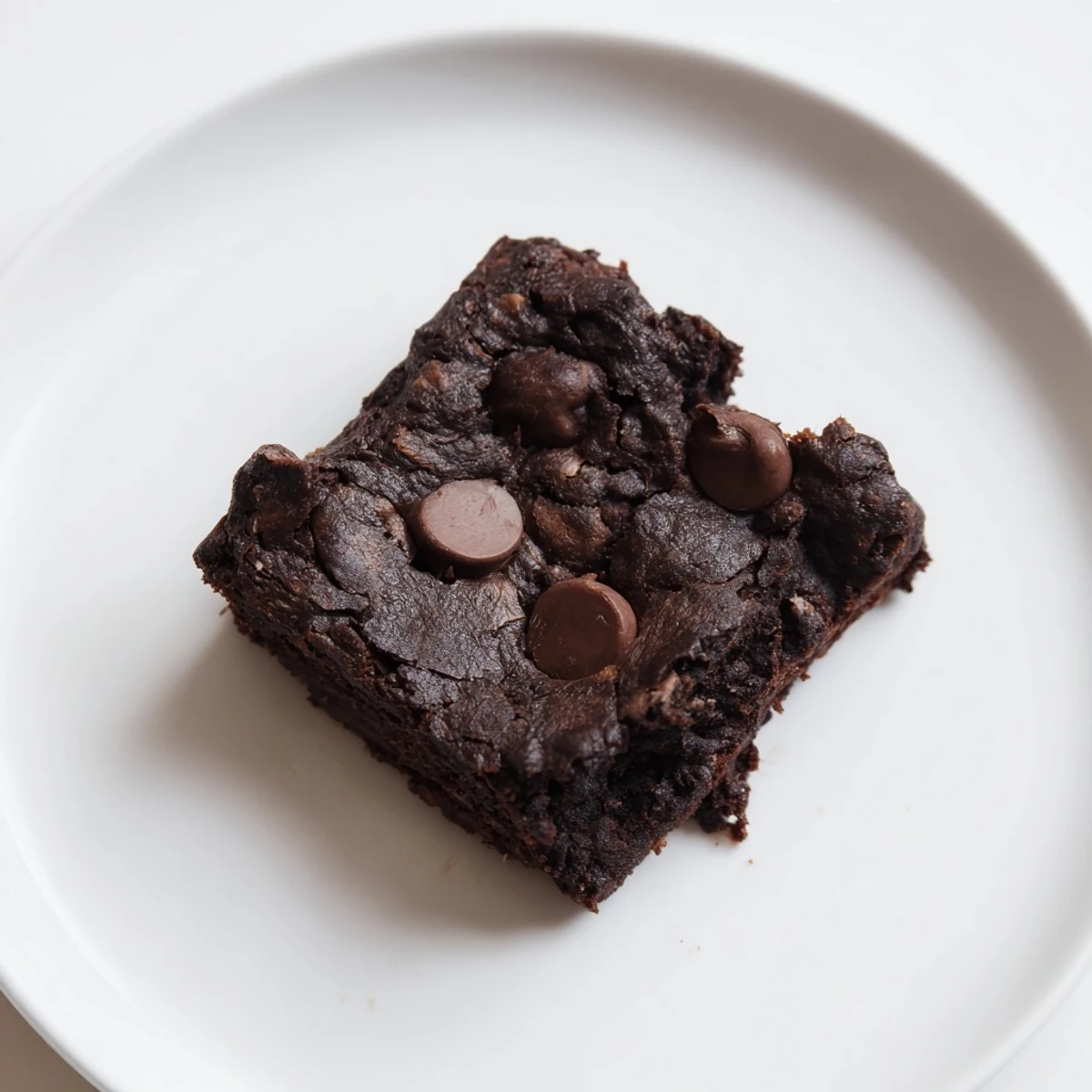 Fudgy Black Bean Brownies, topped with melted chocolate chips, are a delicious gluten-free dessert option.