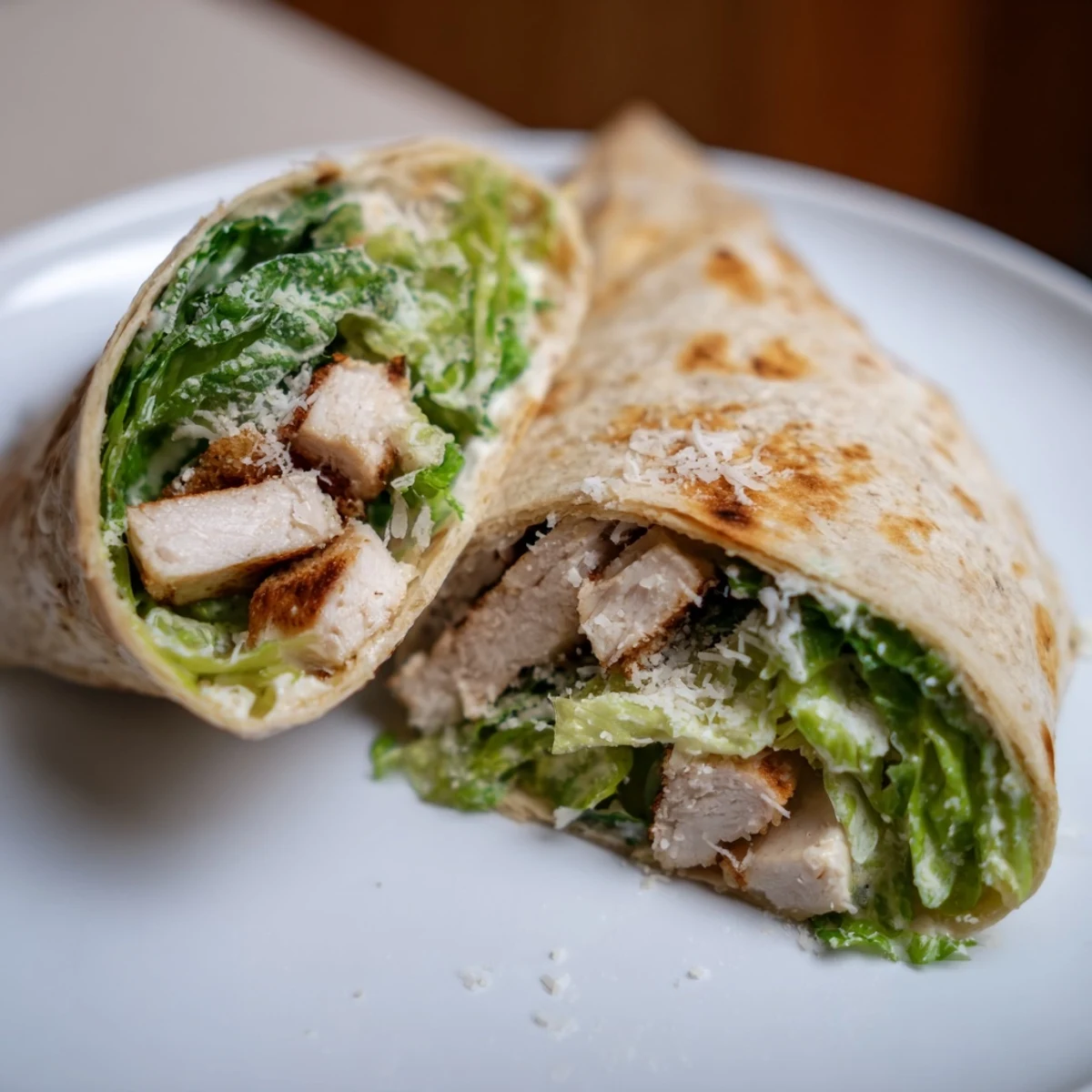 Sliced Chicken Caesar Wraps showcasing the fresh lettuce, chicken pieces, and creamy Caesar dressing inside.