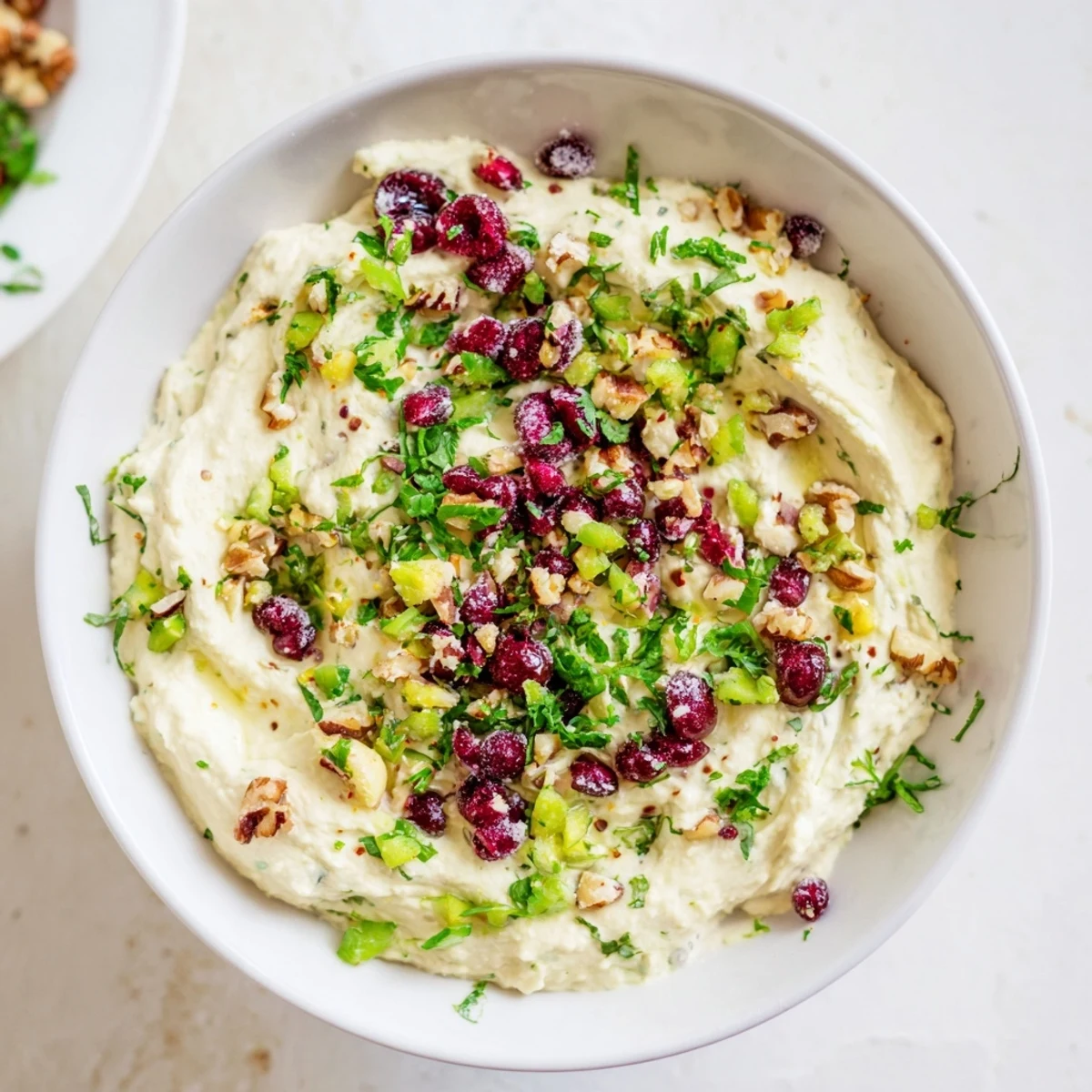 Lightened Holiday Cream Cheese Dip, a creamy appetizer, speckled with red cranberries and green herbs.