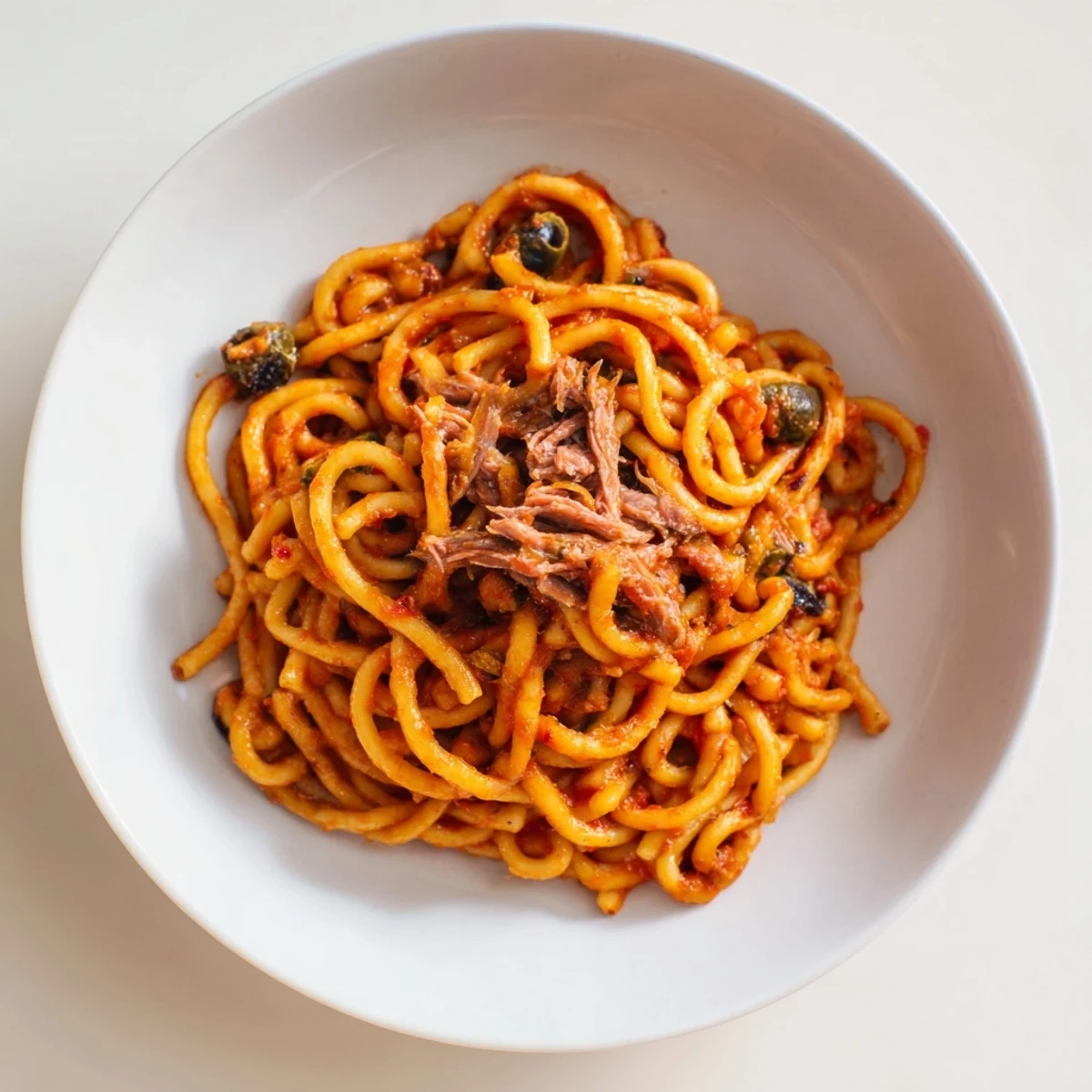 A close-up of perfectly cooked Puttanesca Ditalini pasta, coated in a rich, glistening tomato sauce.