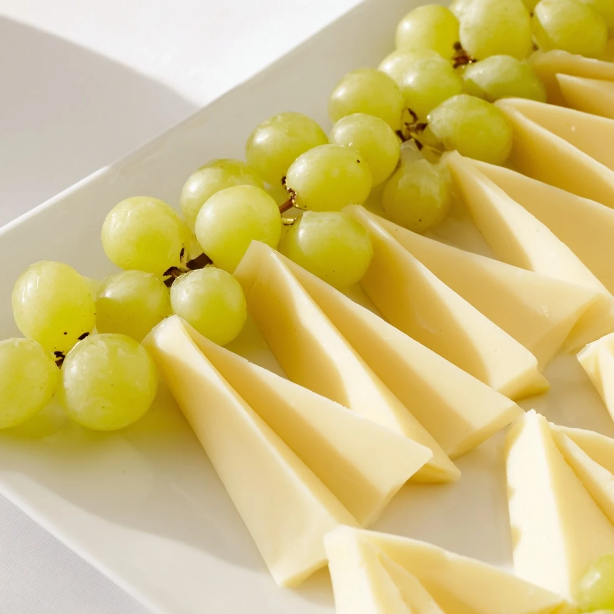 Bright green grapes and cheese triangles create an appealing The Tannenbaum Border holiday appetizer ready to serve.