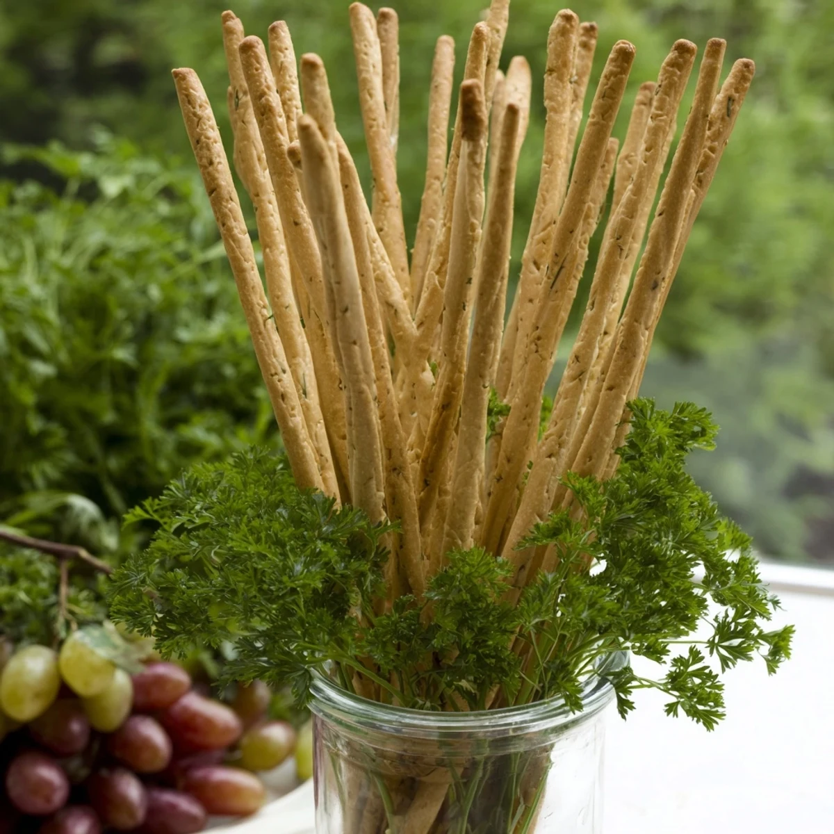 A whimsical view of The Vertical Forest appetizer with upright breadsticks and fresh grape clusters.