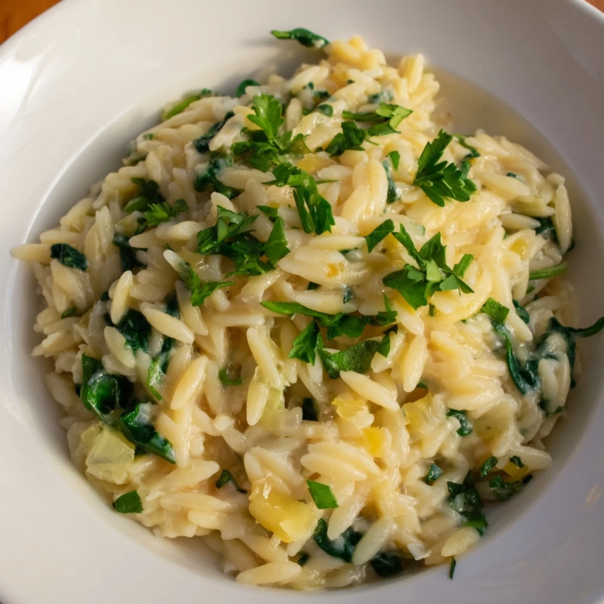 Steaming bowl of one-pot creamy orzo pasta, topped with fresh parsley and Parmesan cheese.