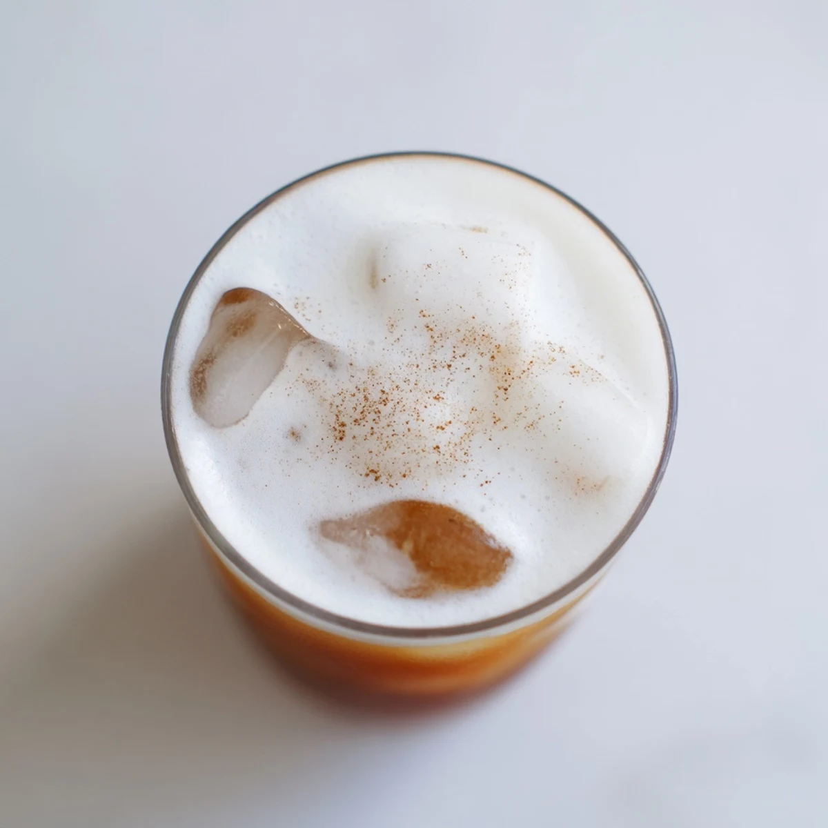 A tall glass filled with ice, amber-colored chai concentrate, and a thick layer of cold foam, perfect for a warm afternoon.