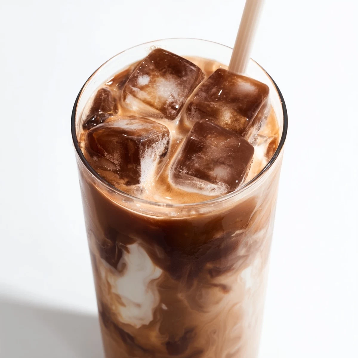 Homemade Milo ice latte in a glass, topped with a straw and ready to enjoy.