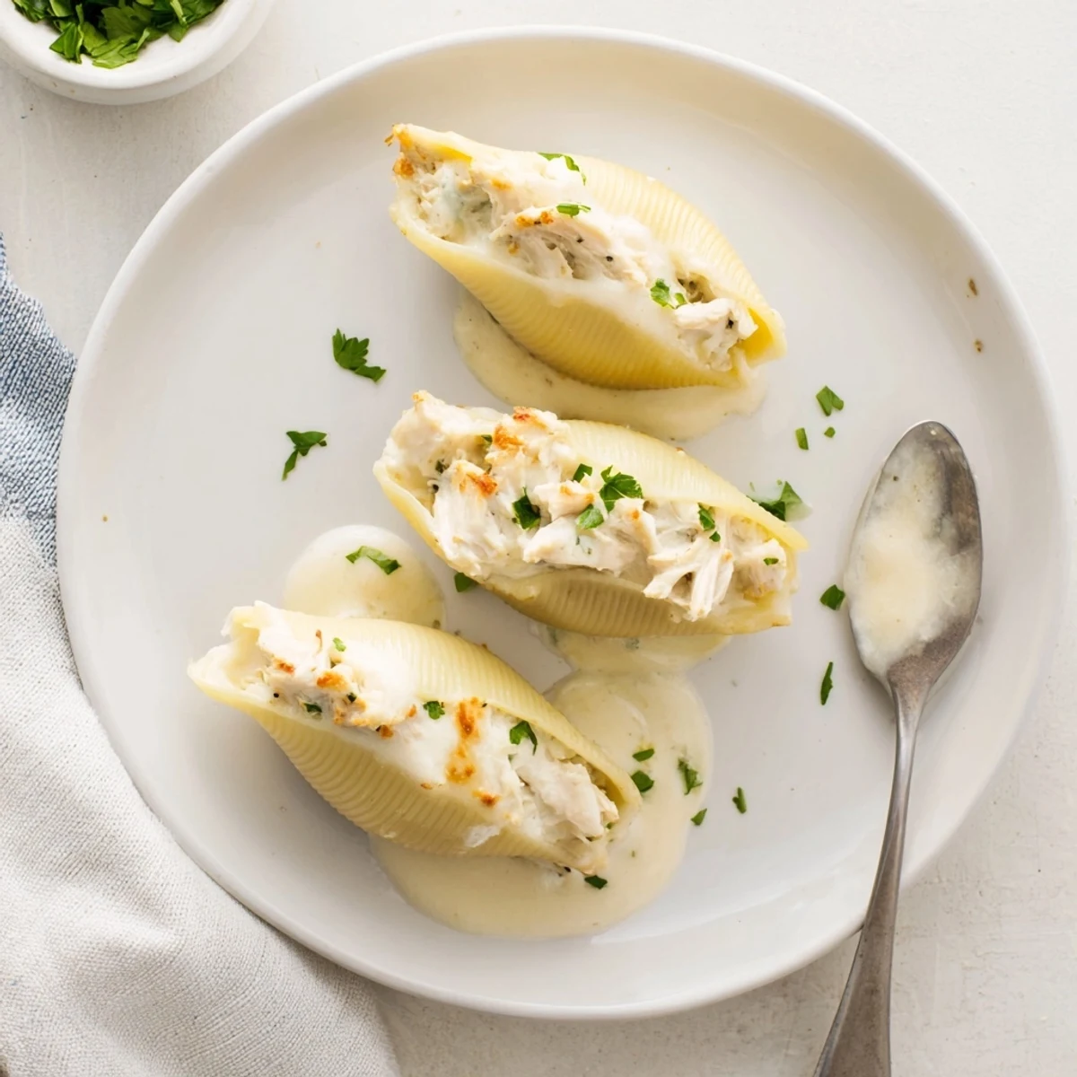 A close-up of Chicken Alfredo Stuffed Shells on a plate, garnished with fresh parsley and garlic bread.
