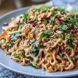 Vibrant Asian Peanut Noodle Bowl with crisp vegetables and creamy peanut dressing, topped with roasted peanuts and sesame seeds.  
