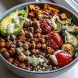 This protein-packed Chickpea Power Bowl features fluffy quinoa, roasted vegetables, and creamy tahini sauce drizzled generously over the top.