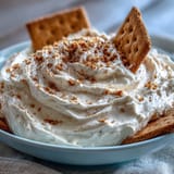 Rich and fluffy cheesecake dip served with crunchy graham crackers, perfect for parties or snacking.  