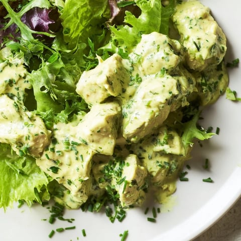 Golden grilled chicken chunks tossed with creamy avocado ranch dressing, fresh cherry tomatoes, and crisp cucumber over mixed greens in a vibrant bowl.  