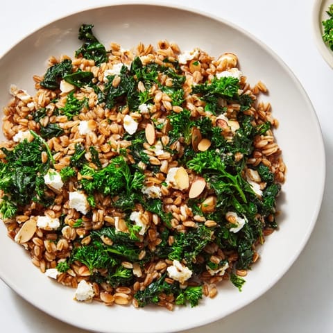 A comforting bowl of Warm Farro & Greens Pilaf, showcasing fluffy farro, fresh herbs, and crunchy almonds.