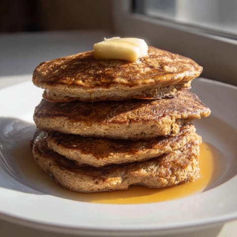 A stack of fluffy Gingerbread Pancakes, drizzled with maple syrup, offering cozy winter vibes.