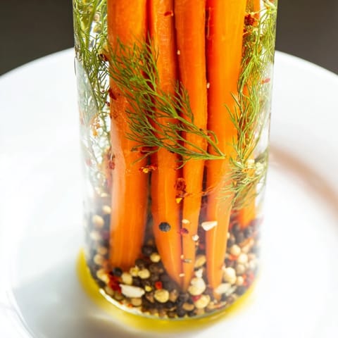 Bright orange Quick Pickled Carrot Spears are showcased, glistening from the tangy vinegar brine.