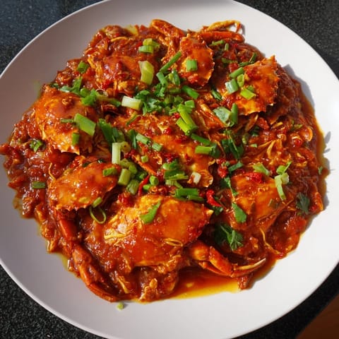 A close-up of savory Singaporean chili crab, showcasing tender crab meat drenched in spicy, glossy sauce.