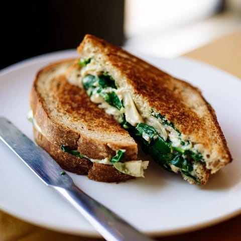 Artichoke Spinach Grilled Cheese sandwich oozing melted mozzarella and Monterey Jack on crisp bread.