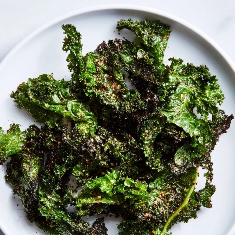 Close-up photo of seasoned olive-oil coated Baked Kale Chips with perfectly curled edges after baking.