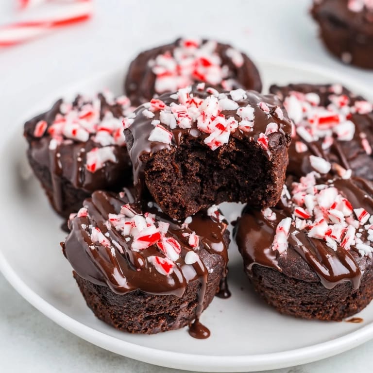 Warm, dark Peppermint Mocha Brownie Bites showing off a glistening glaze and crunchy peppermint candy topping.