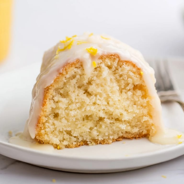 Freshly baked Lemon Yogurt Cake, hinting at lemon zest, served with optional berries and whipped cream.