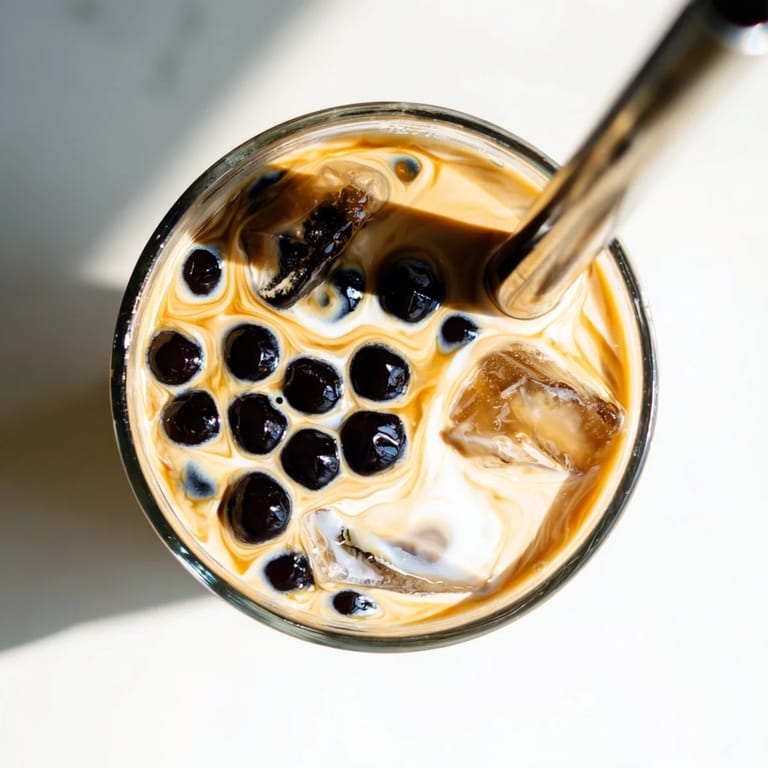 Steaming black tea swirls into milk for this Boba Tea Hack – Instant Bubble Tea with Sweetened Condensed Milk, with tapioca pearls in a clear glass.