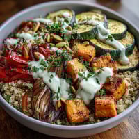 A vibrant Lentil Power Bowl with fluffy quinoa, tender lentils, caramelized roasted vegetables, and a drizzle of creamy tahini dressing.  