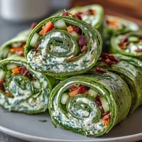 Vibrant spinach tortilla pinwheels filled with herb cream cheese and crisp vegetables for a healthy snack.  